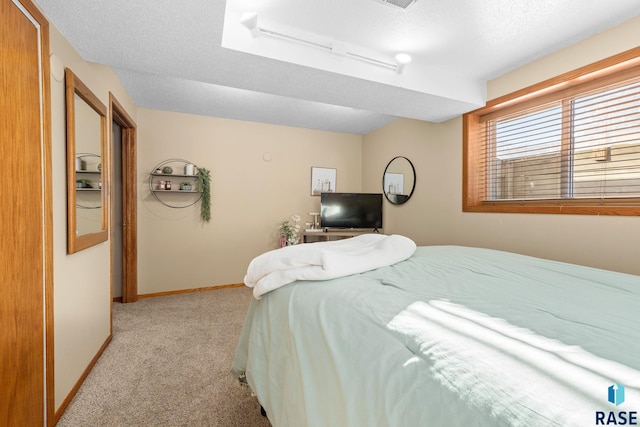 bedroom with a textured ceiling, baseboards, and light colored carpet