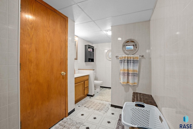 bathroom featuring toilet, tile walls, and vanity