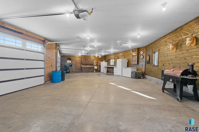 garage featuring wooden walls, a garage door opener, and freestanding refrigerator