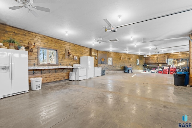 garage featuring ceiling fan, separate washer and dryer, freestanding refrigerator, a garage door opener, and white fridge with ice dispenser