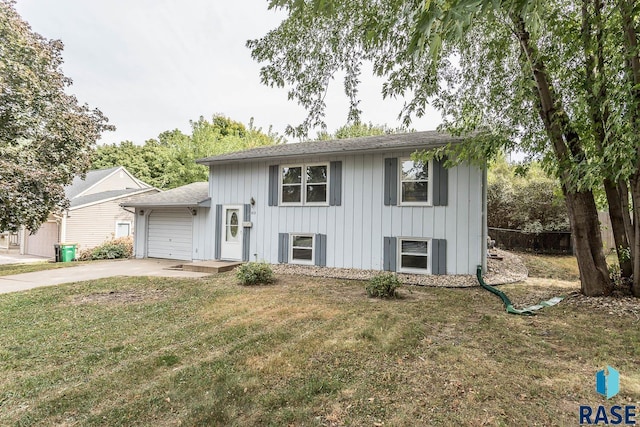 tri-level home with concrete driveway, an attached garage, board and batten siding, fence, and a front lawn