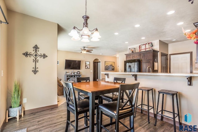 dining area with arched walkways, dark wood finished floors, recessed lighting, ceiling fan, and baseboards