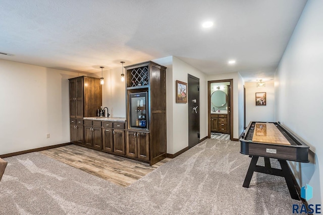 interior space with baseboards, indoor wet bar, a sink, and light colored carpet