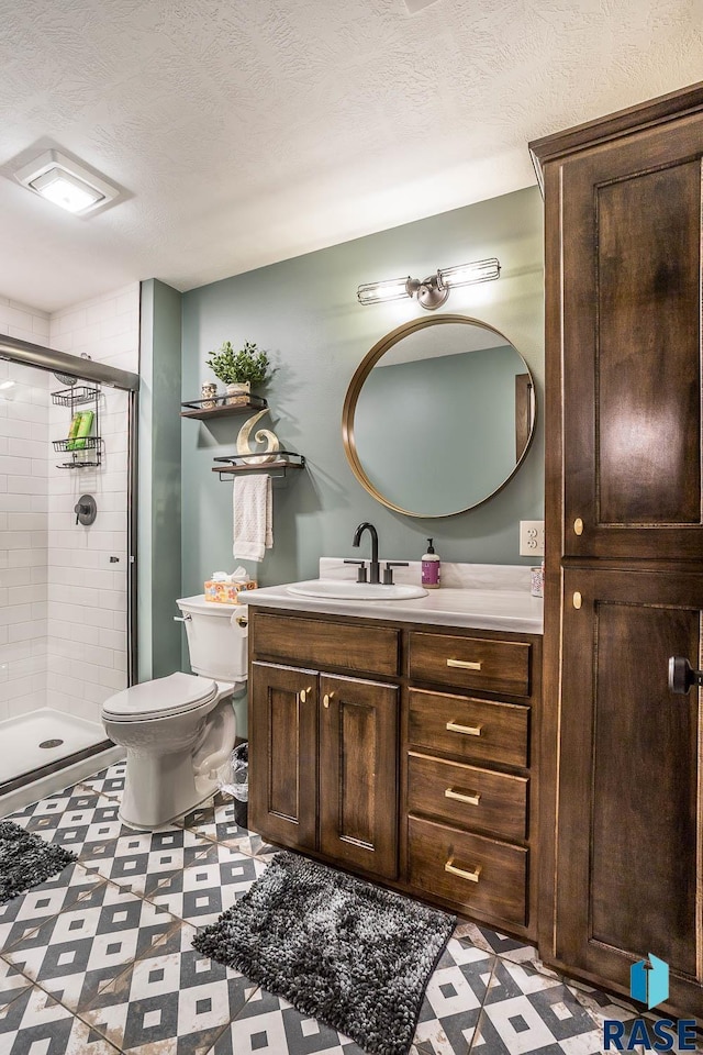 full bathroom featuring a shower stall, vanity, a textured ceiling, and tile patterned floors