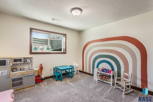 playroom with carpet floors, visible vents, a textured ceiling, and baseboards