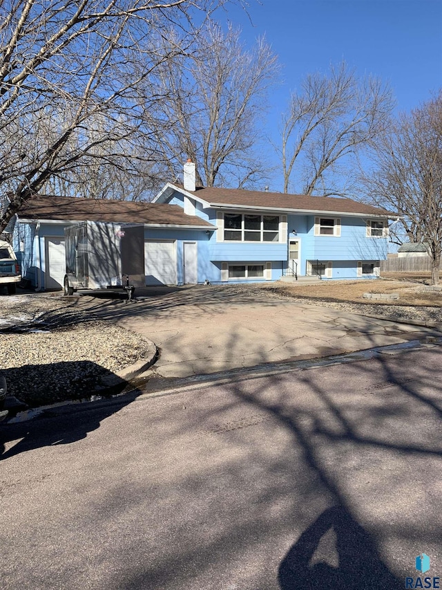 split foyer home featuring driveway and a chimney