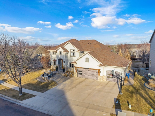 view of front of home with a garage, concrete driveway, stone siding, roof with shingles, and stucco siding