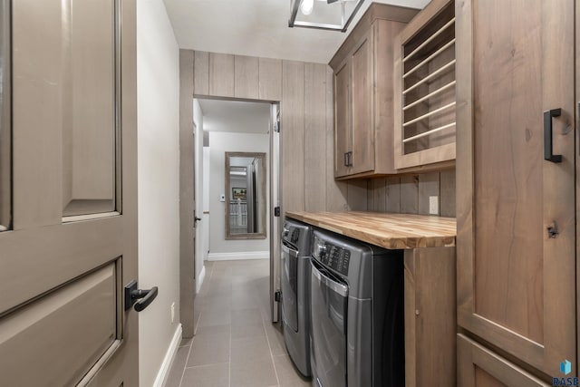 laundry room featuring cabinet space, washer and clothes dryer, baseboards, and light tile patterned flooring