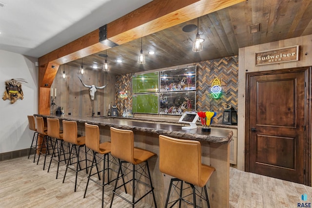 bar with baseboards, indoor wet bar, and wood finished floors