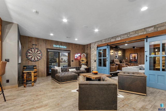 living area with recessed lighting, wood finished floors, wooden walls, and a barn door