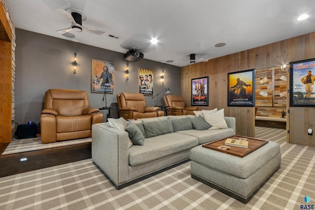 carpeted cinema featuring a ceiling fan, recessed lighting, visible vents, and wooden walls