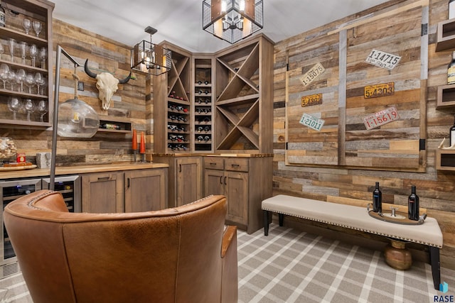 wine cellar with a dry bar, wood walls, and light colored carpet