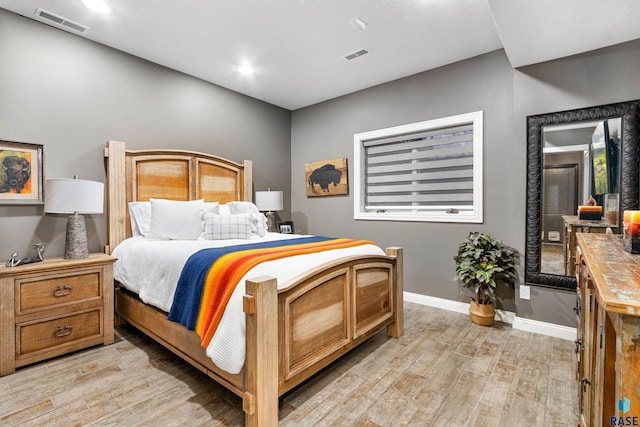 bedroom featuring light wood-type flooring, visible vents, and baseboards