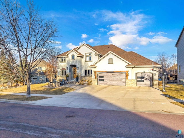 view of front of house featuring driveway, stone siding, an attached garage, and stucco siding