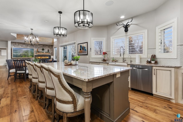 kitchen with a sink, light wood-style floors, dishwasher, and a center island