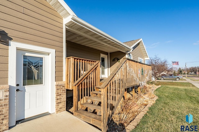 doorway to property with a lawn and brick siding