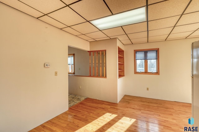 spare room featuring a drop ceiling and hardwood / wood-style flooring