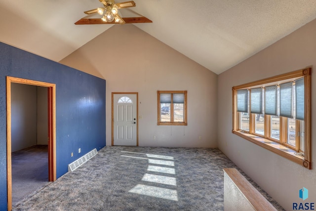 carpeted foyer with a ceiling fan, visible vents, and high vaulted ceiling