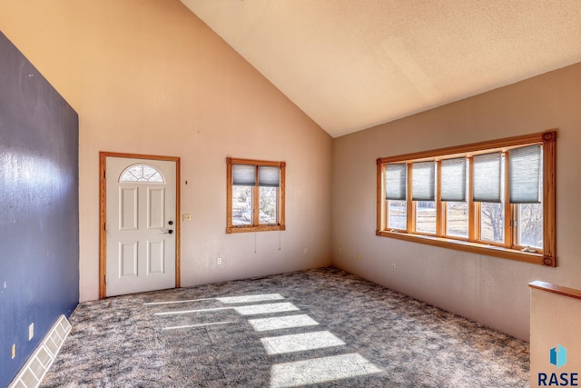 carpeted foyer with visible vents, high vaulted ceiling, and a wealth of natural light