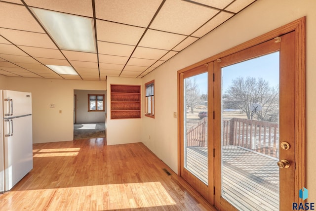 interior space with a paneled ceiling, light wood-style flooring, and visible vents