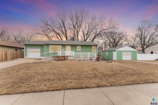 view of front of property featuring driveway, a garage, covered porch, fence, and an outdoor structure