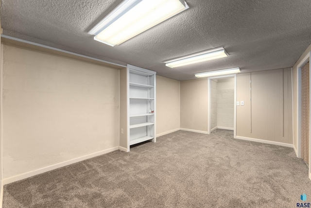 finished below grade area featuring carpet, baseboards, and a textured ceiling