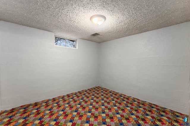 below grade area with carpet floors, visible vents, and a textured ceiling