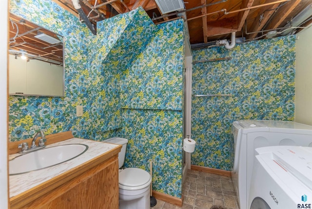 bathroom with wallpapered walls, baseboards, toilet, independent washer and dryer, and vanity