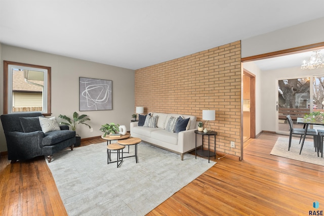 living room featuring light wood-type flooring, baseboards, and an inviting chandelier