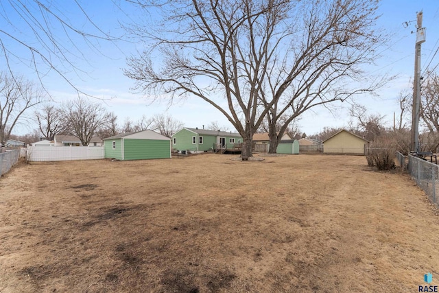 view of yard featuring a fenced backyard, a shed, and an outbuilding