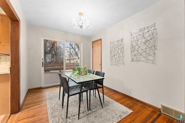 dining space featuring an inviting chandelier, baseboards, visible vents, and wood finished floors