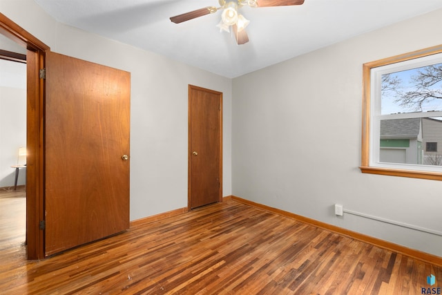 unfurnished bedroom with ceiling fan, a closet, baseboards, and wood finished floors