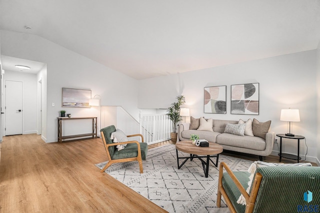 living room with light wood-style floors, lofted ceiling, and baseboards