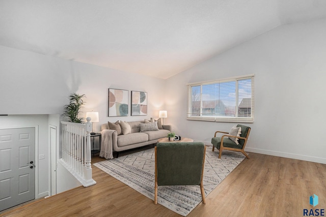 living area with vaulted ceiling, baseboards, and wood finished floors