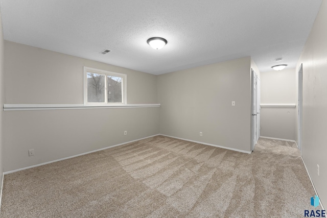 carpeted empty room featuring visible vents, baseboards, and a textured ceiling