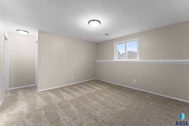 empty room with baseboards, visible vents, a textured ceiling, and carpet flooring