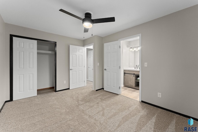 unfurnished bedroom with a closet, light colored carpet, ensuite bathroom, a ceiling fan, and baseboards