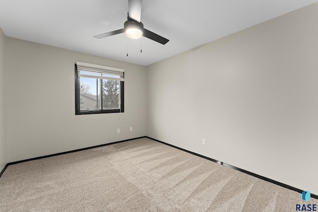 carpeted empty room featuring a ceiling fan and baseboards