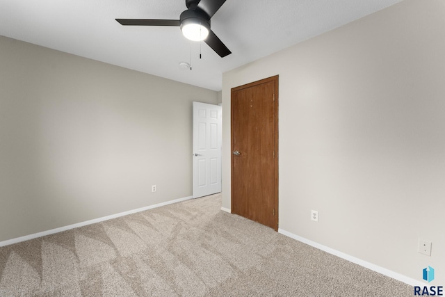 carpeted empty room featuring a ceiling fan and baseboards