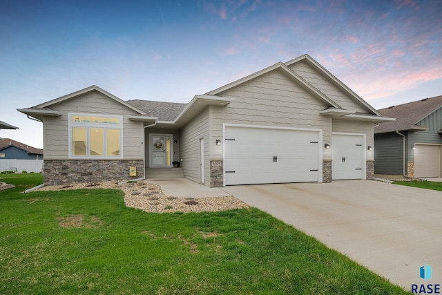 view of front of house with driveway, stone siding, an attached garage, and a lawn