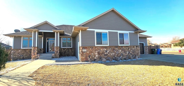 view of front of home featuring a front lawn, fence, concrete driveway, a garage, and stone siding