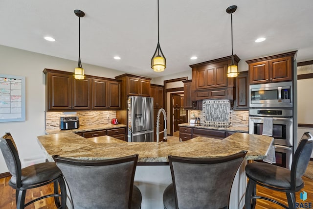 kitchen featuring hanging light fixtures, appliances with stainless steel finishes, and a kitchen bar