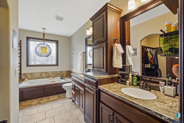 bathroom with visible vents, a walk in closet, a garden tub, tile patterned flooring, and vanity