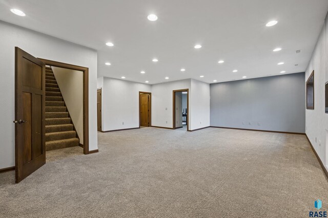 below grade area with light carpet, recessed lighting, stairs, and baseboards
