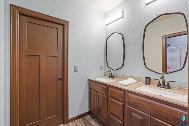 full bath featuring double vanity, wood finished floors, and a sink