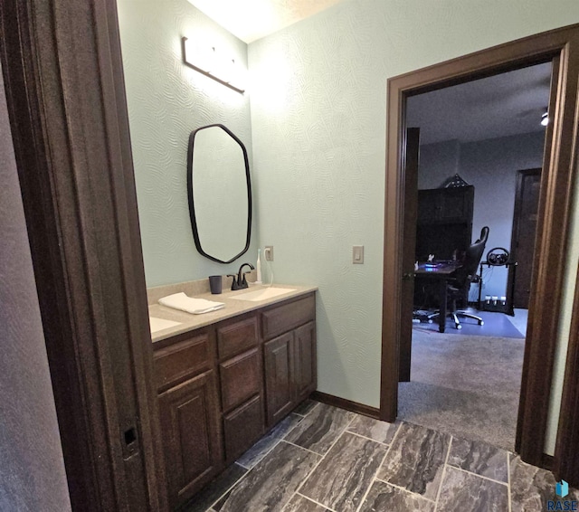bathroom featuring a sink, baseboards, double vanity, and a textured wall