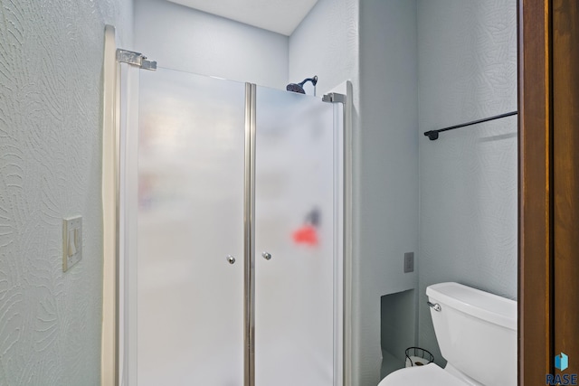 bathroom featuring a shower stall, toilet, and a textured wall