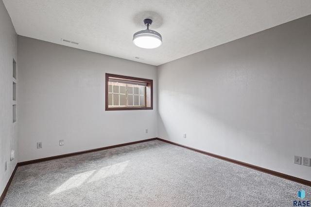 spare room featuring baseboards, visible vents, carpet floors, and a textured ceiling