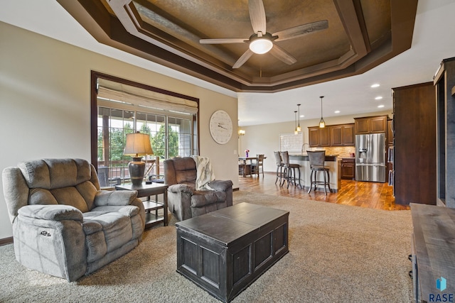living room with a raised ceiling, recessed lighting, and ceiling fan