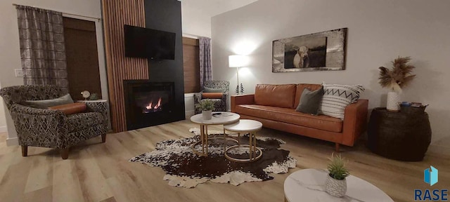 sitting room featuring a glass covered fireplace and wood finished floors